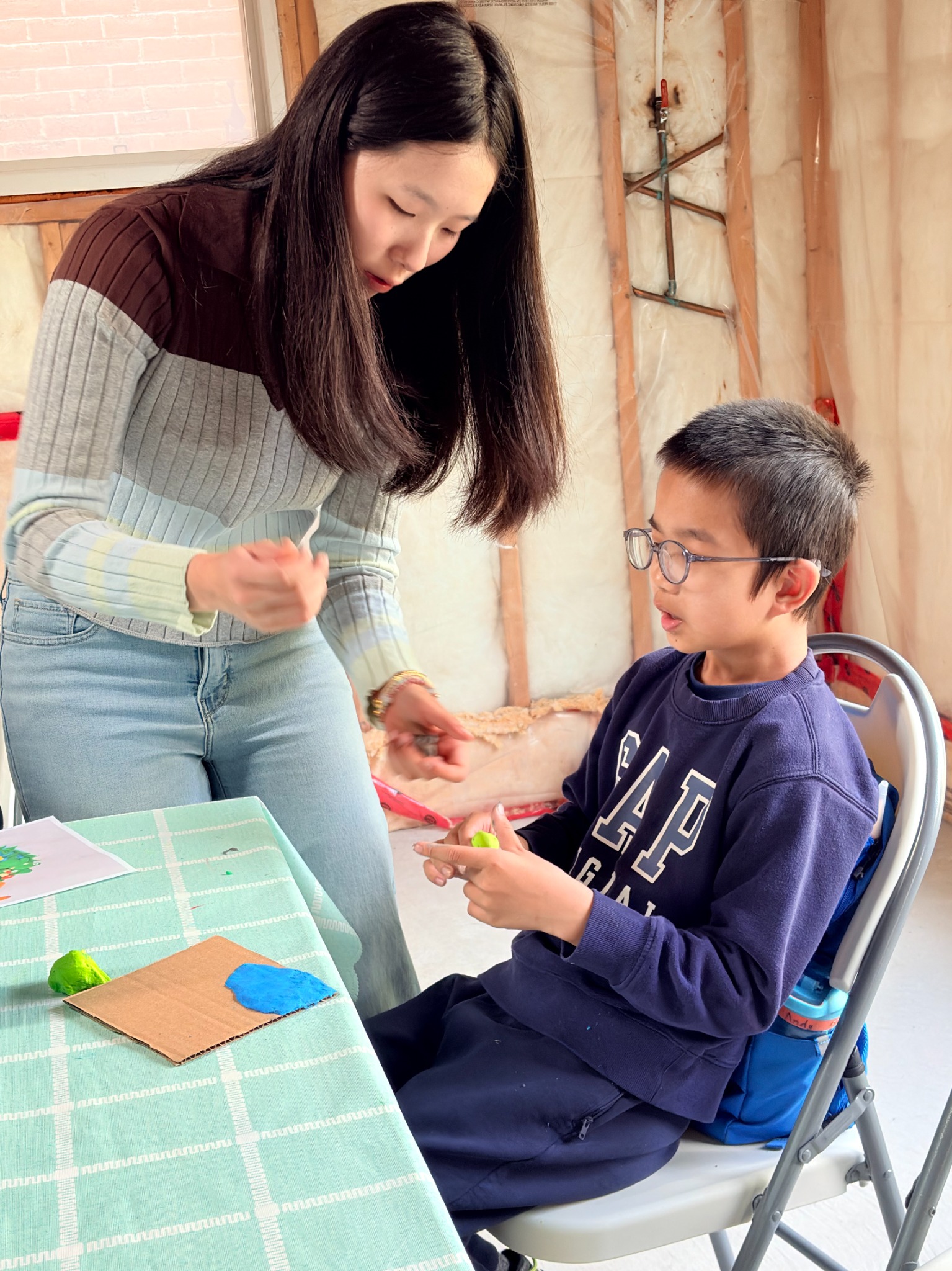 A volunteer helping a child shape colourful clay for a miniature world