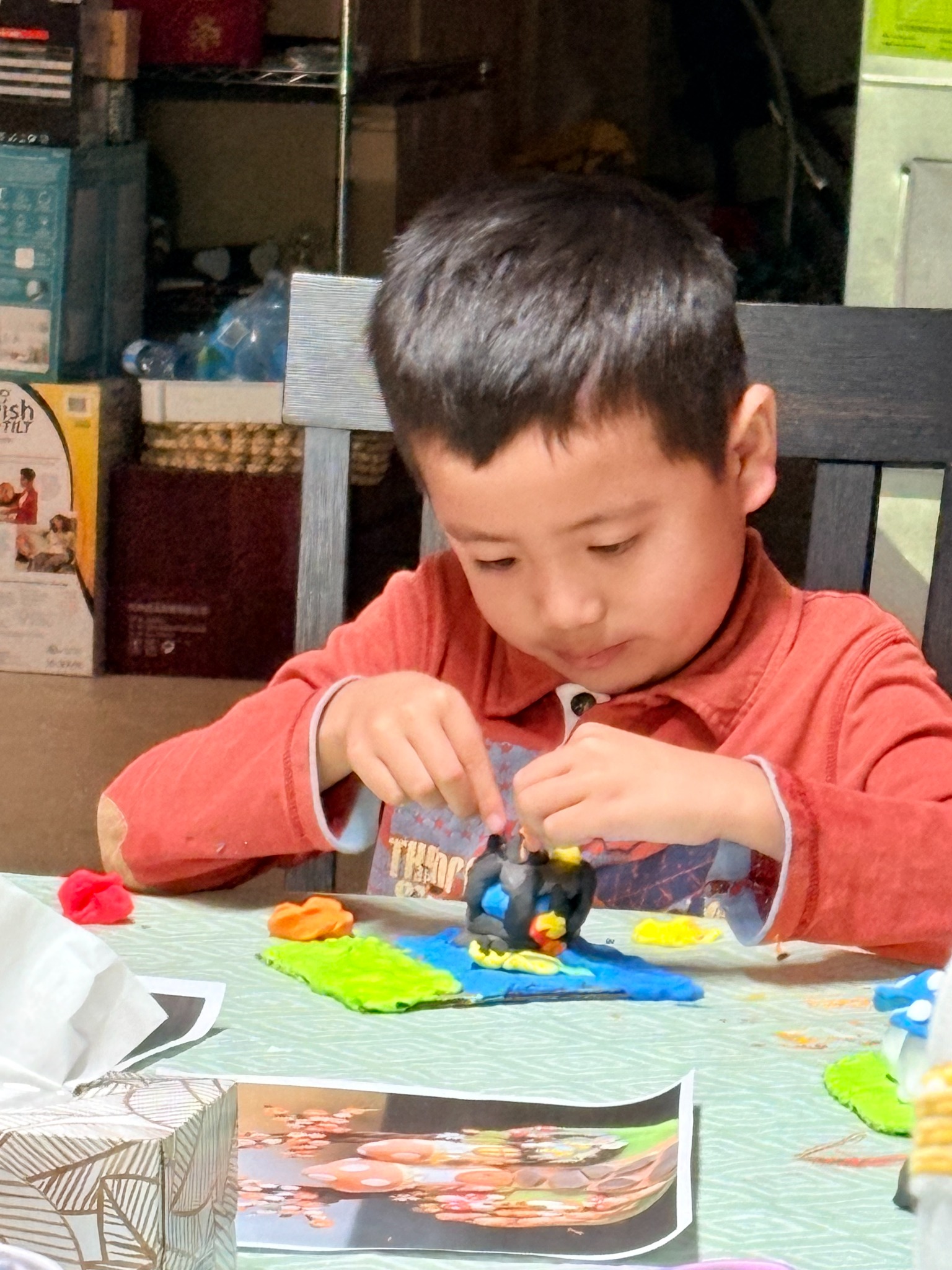 A child adding details to a colourful clay landscape