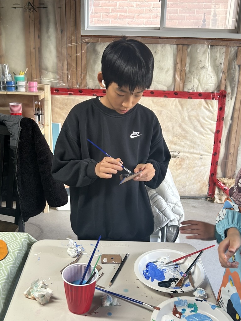 Kevien painting an art project at a YICA workshop