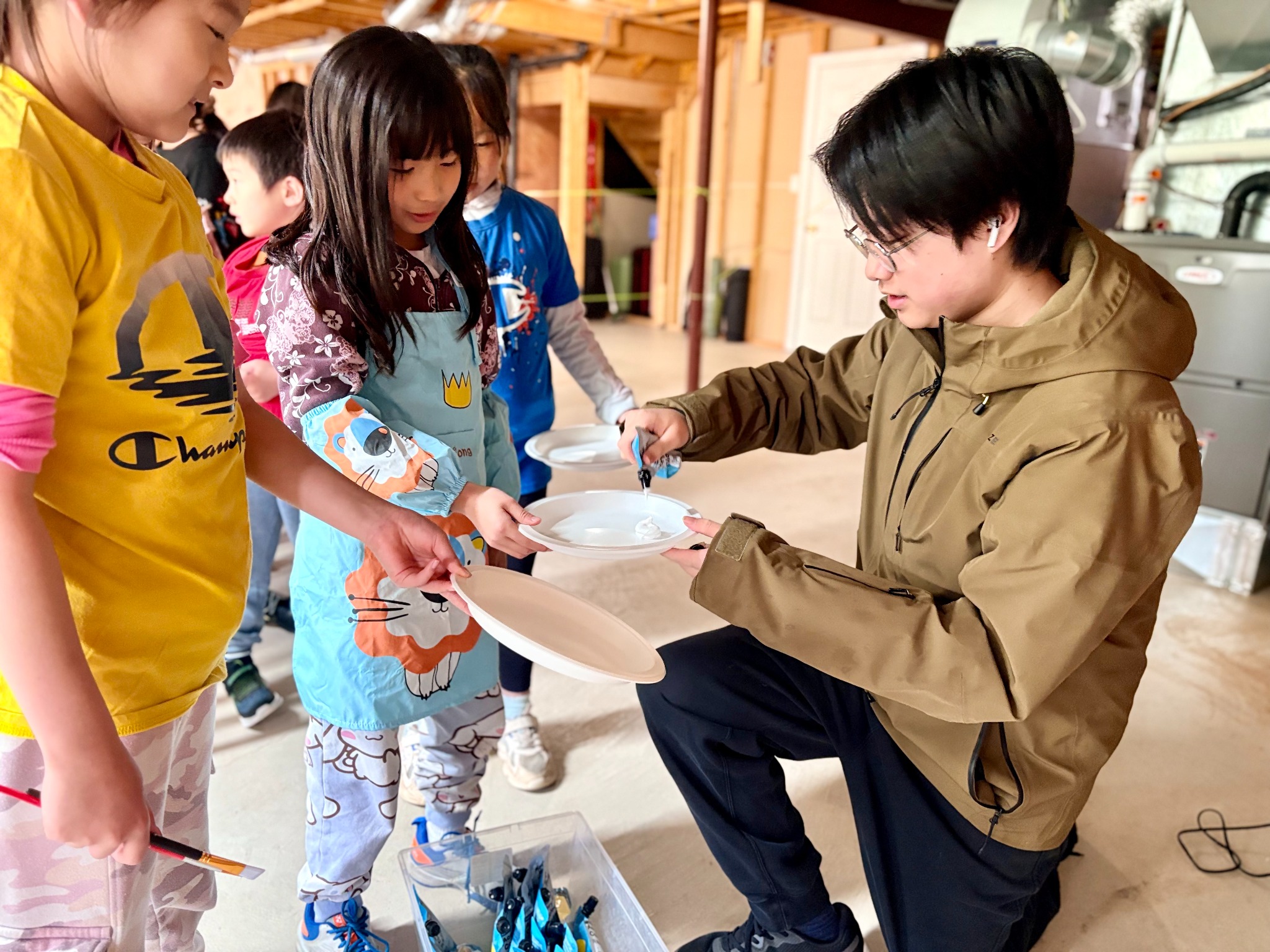 Stephan helping children prepare paint at a YICA art workshop